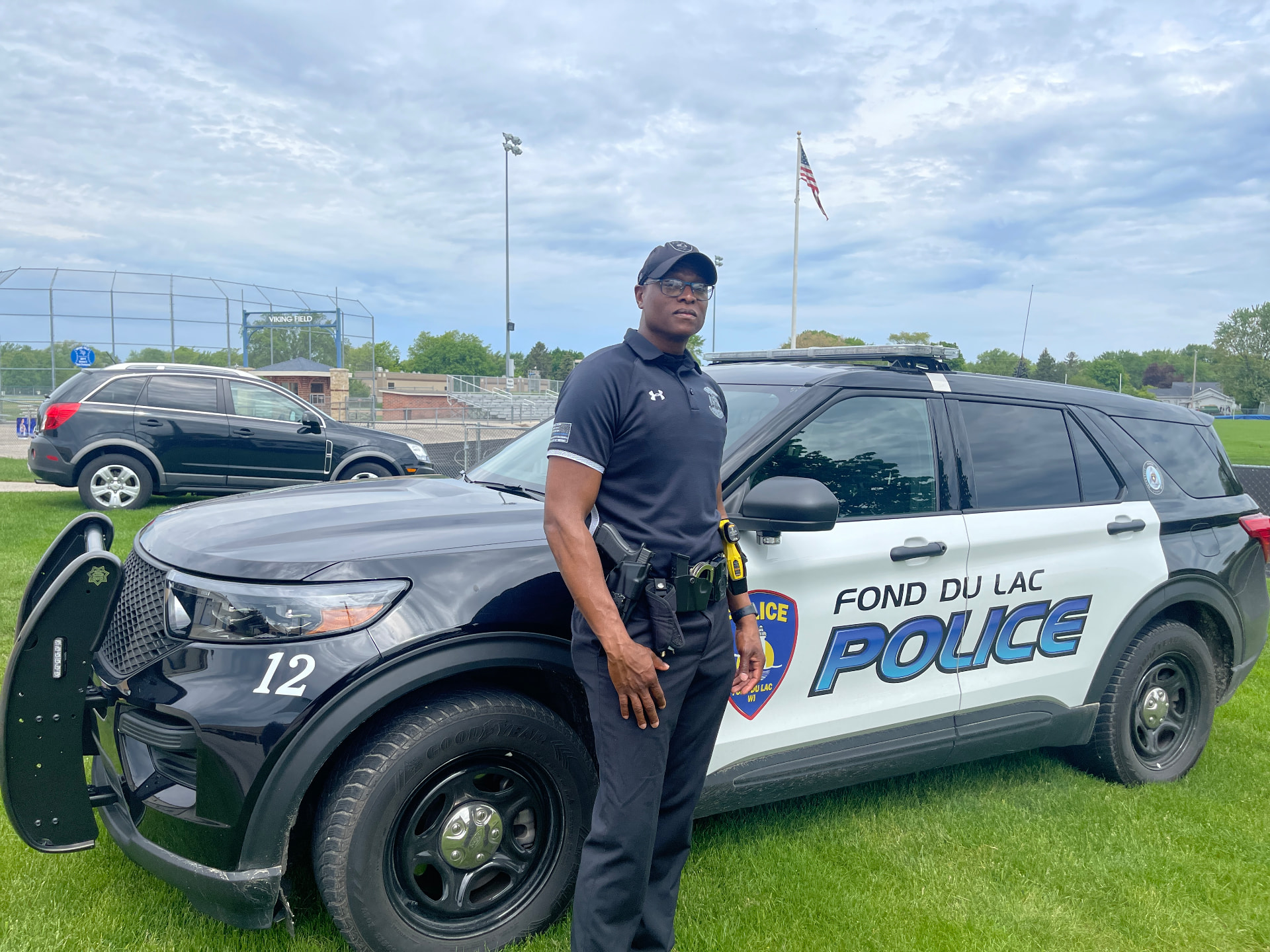 Officer Keywon Brown standing beside a Fond du Lac Police squad vehicle at Viking Field.